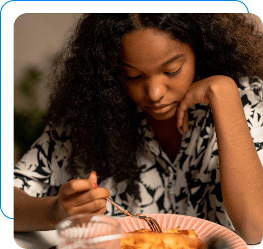 Young woman with an eating disorder looking sad at her food on her plate.