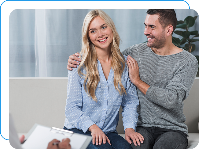 Husband and wife smiling while talking to therapist in affair therapy.