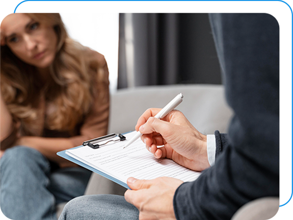 Therapist writing down notes while the client sits in distress on an opposite chair.