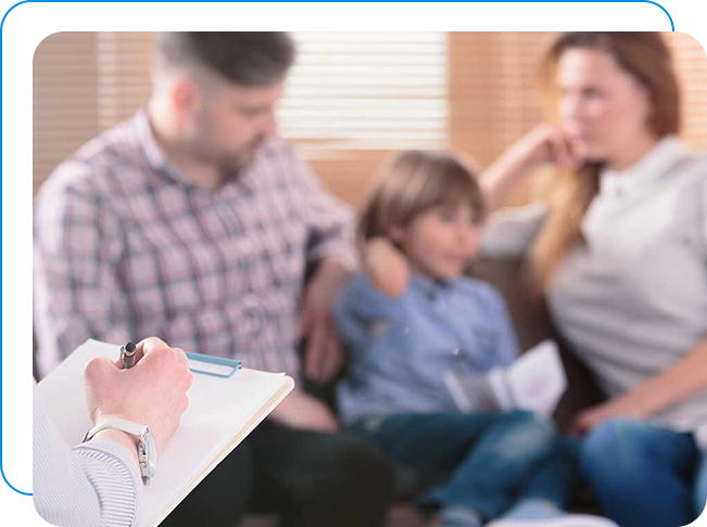 Family sitting on a couch while the therapist takes notes.