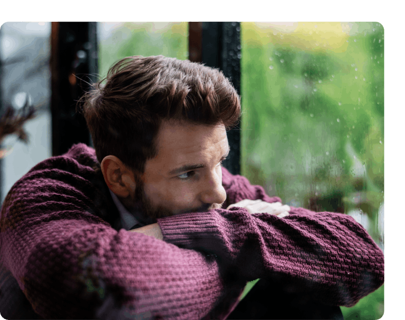 Man with health anxiety sadly looking at rain.