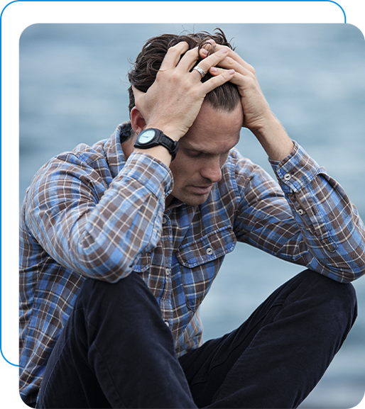 A man looking stressed out while sitting on a step with his hands on his head.